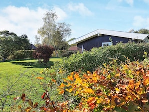 A building with a sloped roof, surrounded by a well-maintained lawn and various shrubs. - Peaceful Holiday Home in Falster near Sea (Vaeggerlose)