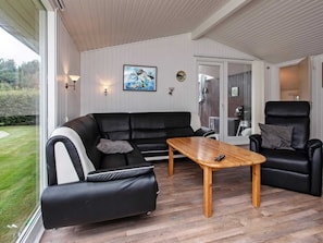 A modern living room with a black leather sofa, a wooden coffee table, and a black leather armchair. - Peaceful Holiday Home in Falster near Sea (Vaeggerlose)