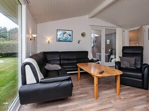 A modern living room with a black leather sofa, a wooden coffee table, and a black leather armchair. - Peaceful Holiday Home in Falster near Sea (Vaeggerlose)