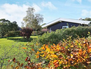 A building with a dark exterior and a sloped roof, surrounded by a well-maintained lawn and various shrubs. - Peaceful Holiday Home in Falster near Sea (Vaeggerlose)