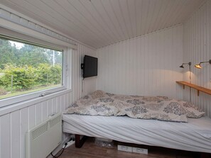 A small room with a bed, a radiator, a window, and a mounted TV. - Peaceful Holiday Home in Falster near Sea (Vaeggerlose)