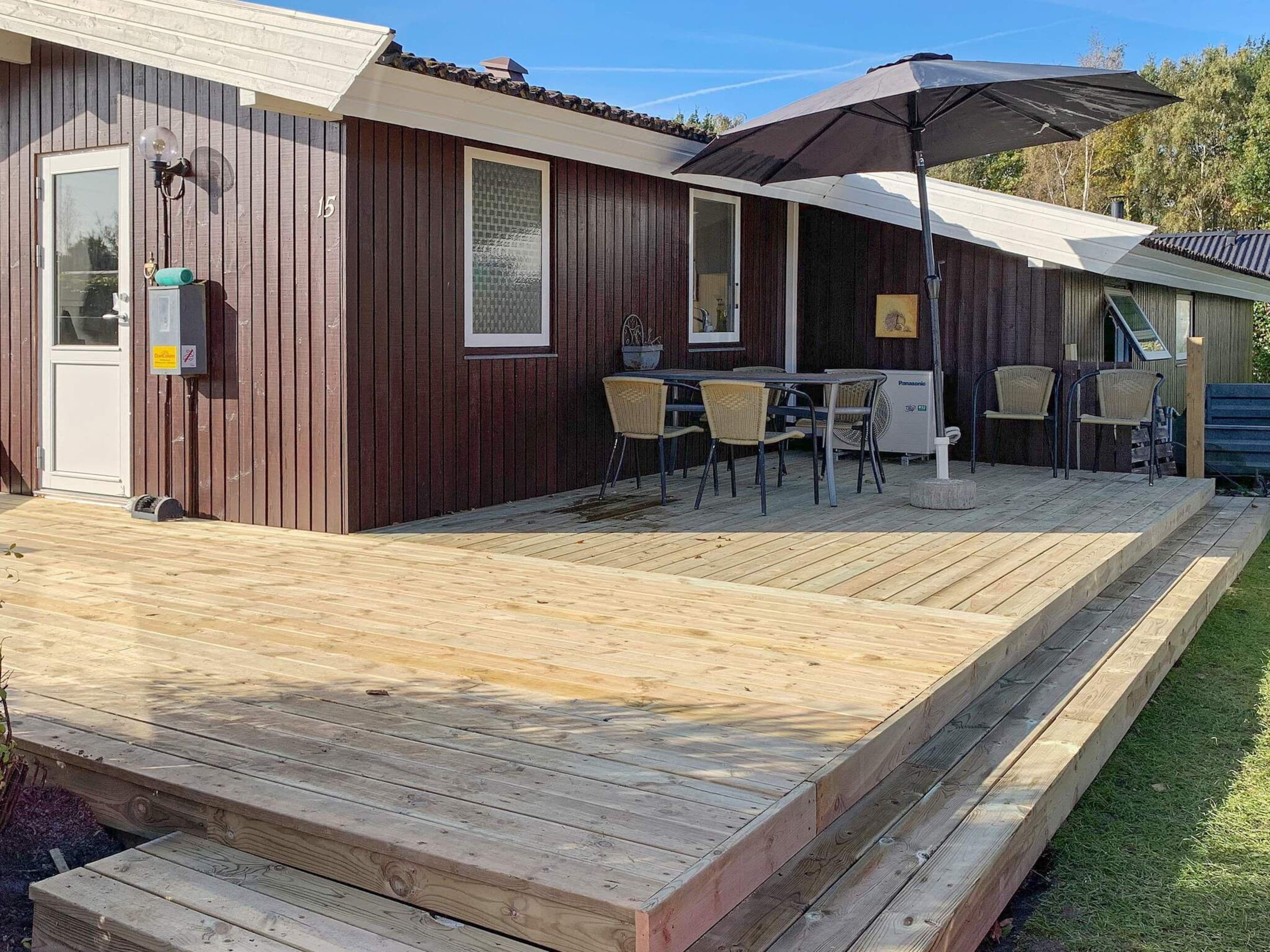 A wooden building with a deck, outdoor seating, and a fan.