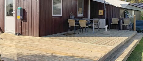 Un edificio de madera con terraza, asientos exteriores y un ventilador.