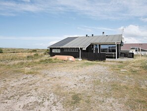 A single-story building with a dark exterior, a visible number '48' on the side, and a satellite dish on the roof. - 6 Person Holiday Home in Lemvig (Lemvig)
