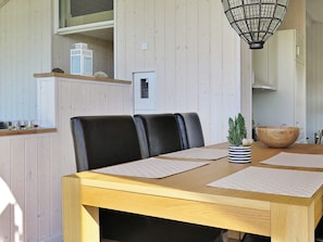 A dining area with a wooden table, black leather chairs, and a hanging light fixture. - 6 Person Holiday Home in Lemvig (Lemvig)