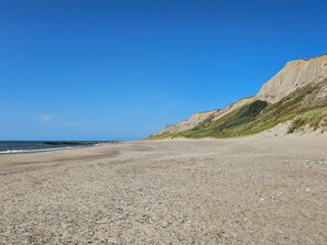 A pebble beach with a clear sky and cliffs in the background. - 6 Person Holiday Home in Lemvig (Lemvig)