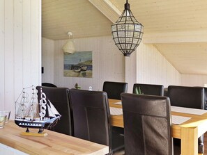 A dining area with a wooden table, black leather chairs, a hanging light fixture, and a painting on the wall. - 6 Person Holiday Home in Lemvig (Lemvig)