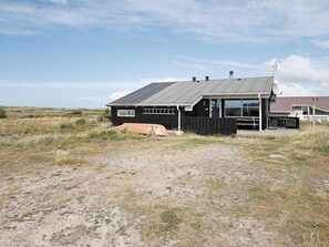 A single-story building with a dark exterior, a visible number '48' on the side, and a satellite dish on the roof. - 6 Person Holiday Home in Lemvig (Lemvig)