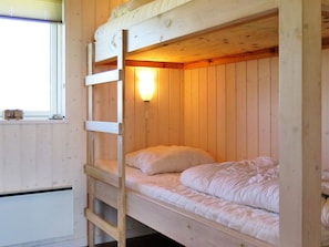 A bunk bed with a ladder, a bedside lamp, and a window with a view.