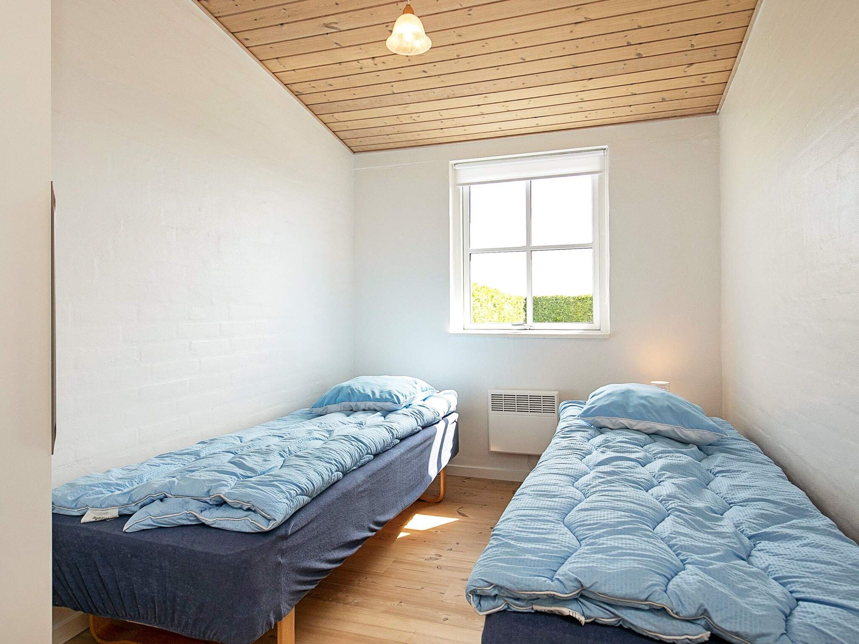 A room with two single beds, a window, and a ceiling fan.