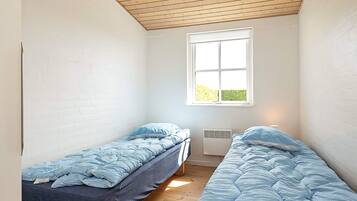 A room with two single beds, a window, and a ceiling fan.