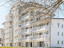 A multi-story building with balconies, a clear sky, and a sign indicating a no parking zone.
