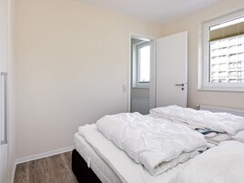 A bedroom with a bed, a window, and a door.