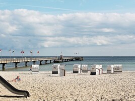 A beach with a pier, beach chairs, and a slide.