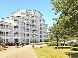 A multi-story hotel with balconies, a parking area, and a well-maintained lawn.