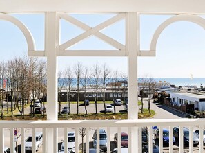 A view through a white structure with a clear sky, a parking lot with cars, and a building in the background. - Holiday Home in Grossenbrode (Grossenbrode)