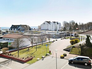 A parking area with a car, a building with a flat roof, and a clear sky. - Holiday Home in Grossenbrode (Grossenbrode)