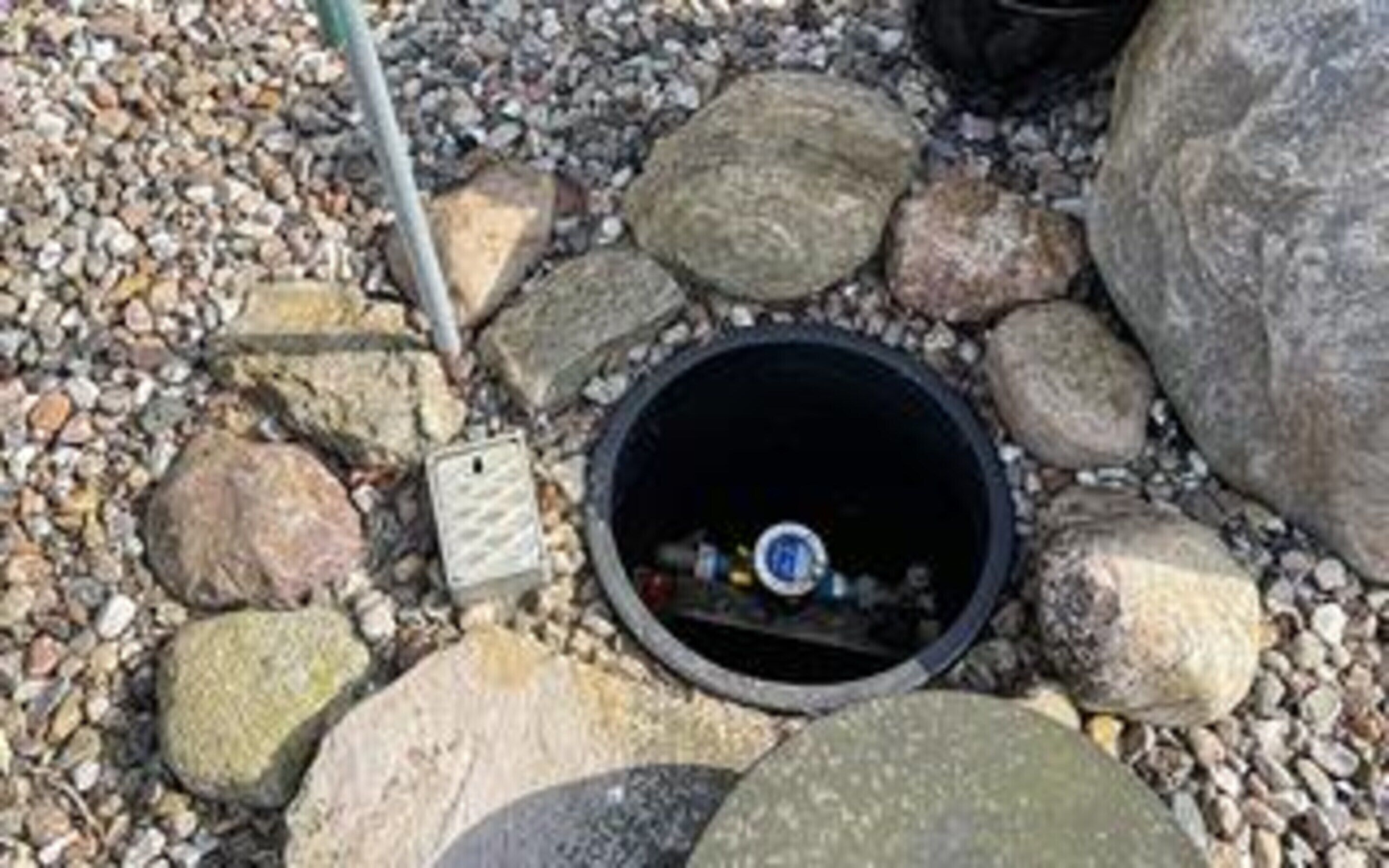 A manhole cover surrounded by rocks and pebbles.
