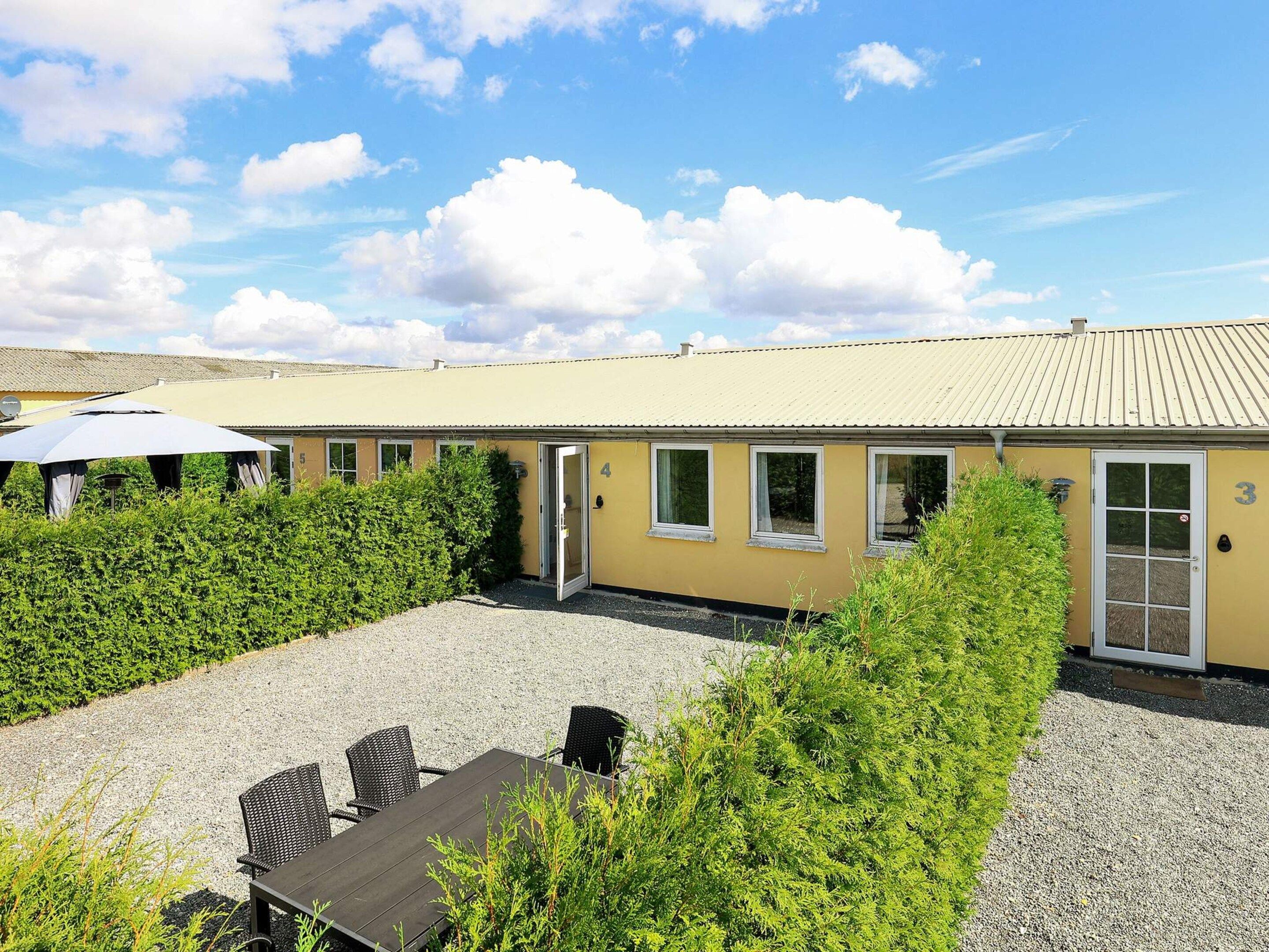 A building with numbered doors, a gravel courtyard, and outdoor seating.