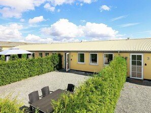 A building with numbered doors, a gravel courtyard, and outdoor seating. - 6 Person Holiday Home in Faaborg (Faaborg)