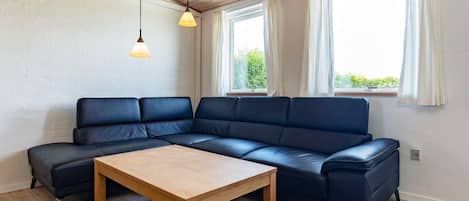 A modern living room with a sectional sofa, a wooden coffee table, and two pendant lights.