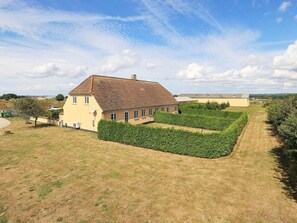 A two-story house with a tiled roof, surrounded by a well-maintained garden and a clear sky.