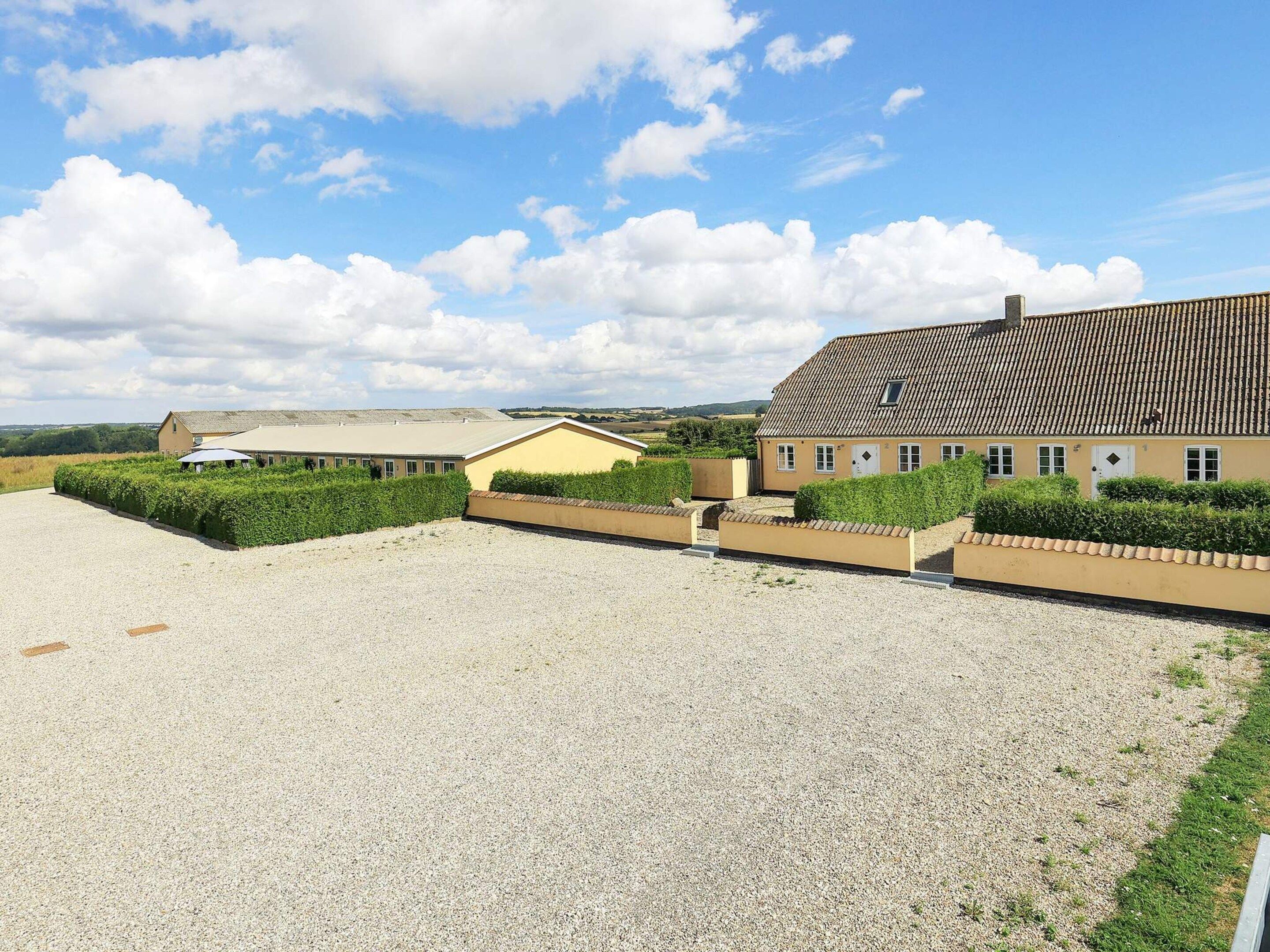 A gravel courtyard with buildings, one with a tiled roof and another with a flat roof.