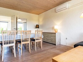 A dining area with wooden chairs and a table, a lamp, and a wall-mounted air conditioner.