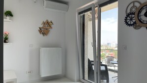 A modern room with a sliding glass door leading to an outdoor area, a radiator, and decorative wall art. - Westpark 2 Luxury Studio-Suite with Lakeview W5 (Sector 6)