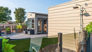 Un patio moderno al aire libre con terraza de madera, zona de estar y puerta de cristal.