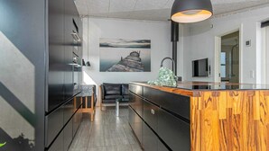 Una cocina moderna con una isla de madera, armarios negros y un cuadro grande en la pared.