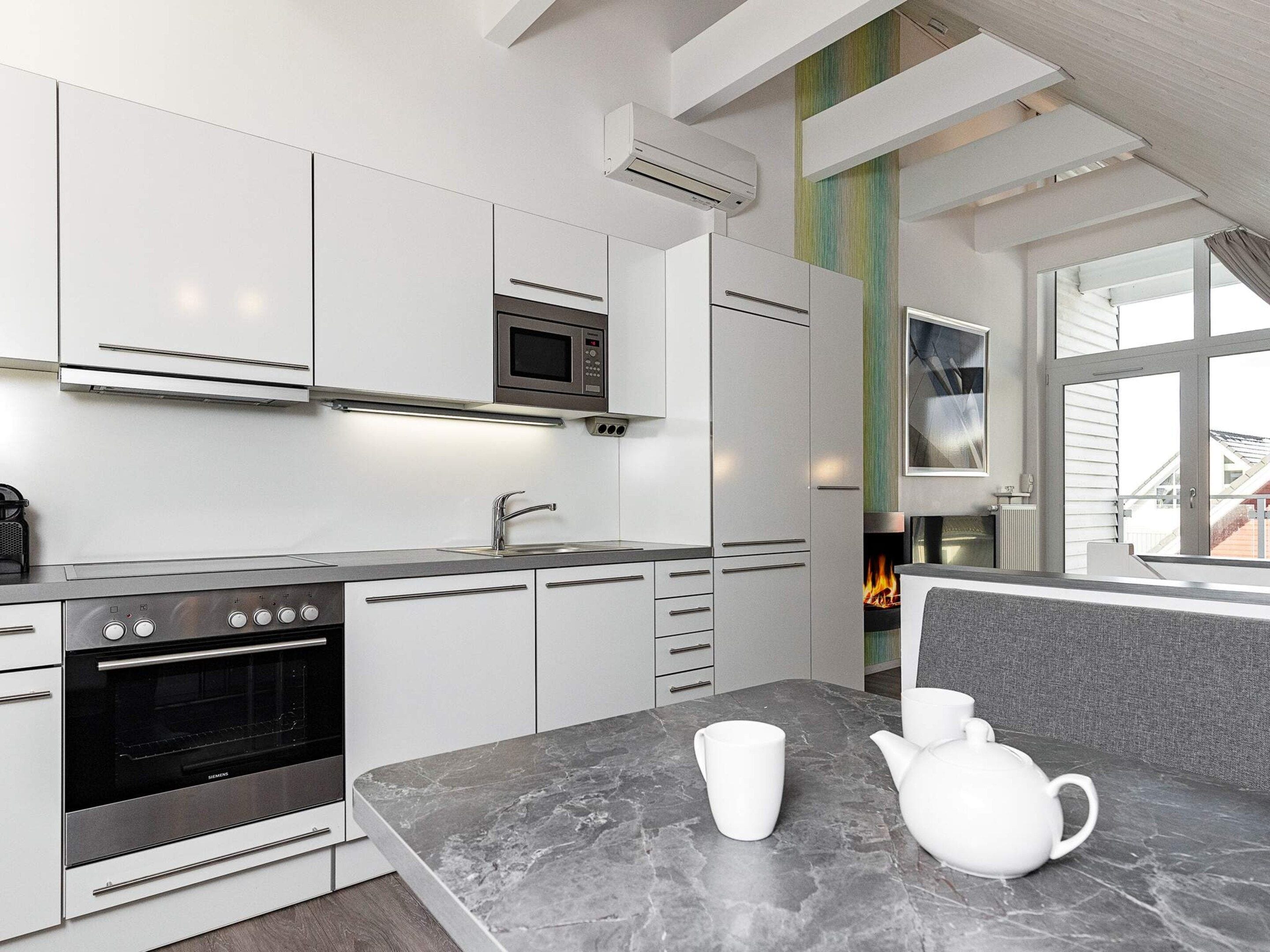 A modern kitchen with white cabinetry, a built-in oven, and a microwave.