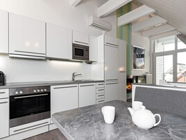 Una cocina moderna con armarios blancos, horno empotrado y microondas.