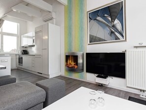 A modern living room with a fireplace, a flat-screen TV, and a colorful vertical wall.