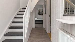 A staircase with white railings and dark steps, leading to a room with a bed and a window. - Holiday Home in Wendtorf (Wendtorf)