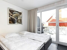 Una habitación de hotel con una cama, un ventanal grande y un cuadro en la pared.