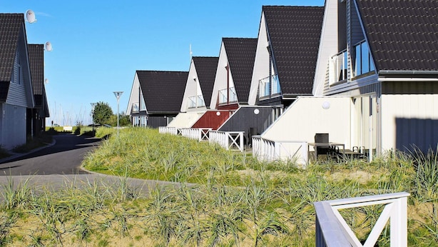 A row of modern houses with sloped roofs, a paved road, and a grassy area in the foreground. - Holiday Home in Wendtorf (Wendtorf)