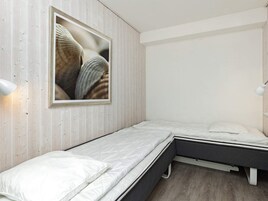 Un dormitorio con una cama, una lámpara de noche y un cuadro en la pared.