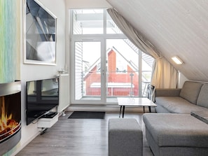 A modern living room with a fireplace, a large window, and a view of a red building.