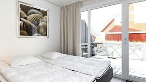 A modern hotel room with a large bed, a sliding glass door to the outside, and a framed artwork on the wall. - Holiday Home in Wendtorf (Wendtorf)