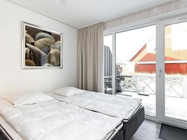 Una habitación de hotel moderna con una cama grande, una puerta corrediza de vidrio al exterior y una obra de arte enmarcada en la pared.