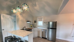 A modern kitchen with a marble countertop, stainless steel appliances, and a bar stool seating area.