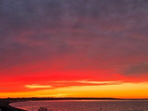 A sunset over a body of water with a distant shoreline.