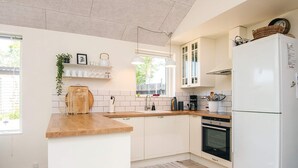 A modern kitchen with white cabinets, a wooden countertop, a built-in oven, and a white refrigerator. - Cozy Holiday Home in Haderslev near Beach (Haderslev)