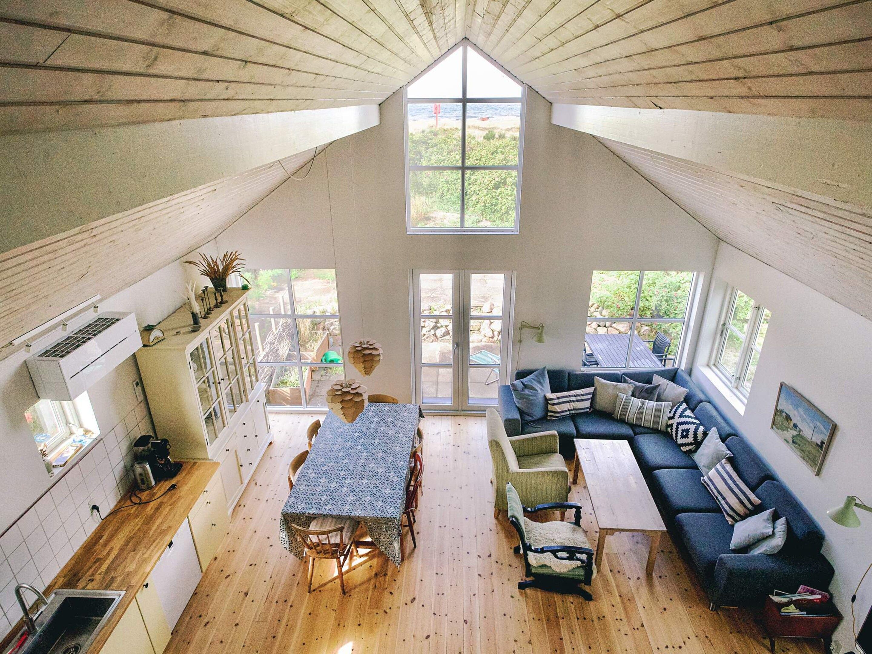 Un intérieur de style industriel, avec un espace repas, des sièges et de grandes fenêtres.