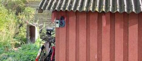A red building with a corrugated metal roof, a bicycle parked outside, and a small sign on the wall.