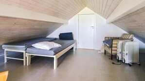 A small attic bedroom with a sloped ceiling, a single bed, a radiator, and a door. - 6 Person Holiday Home in Store Fuglede (Store Fuglede)