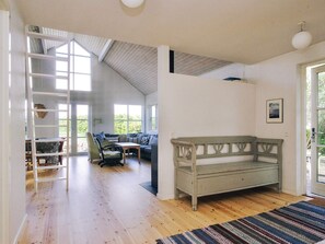 Ein geräumiges Zimmer mit Schlafgalerie, einer Holzbank, einem Sofa und einem Esstisch.