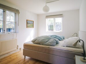 A bedroom with a bed, a radiator, and two windows with blinds. - 6 Person Holiday Home in Store Fuglede (Store Fuglede)