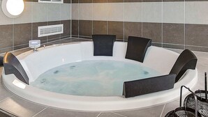 A modern bathroom with a freestanding bathtub, a round mirror, and a wall-mounted heater. - Holiday Home in Kappeln (Kappeln)